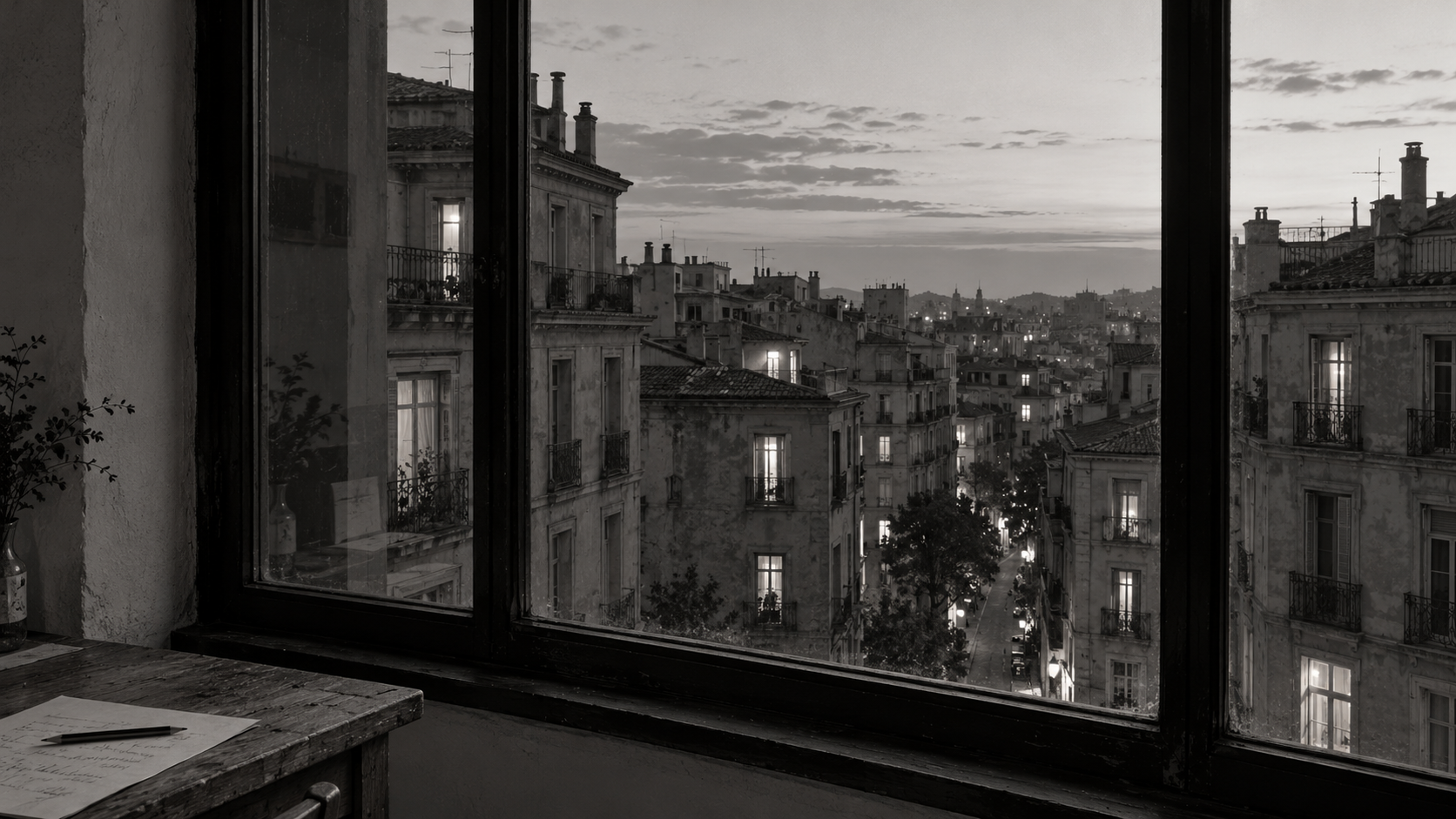 An unfamiliar city at dusk through a workspace window, with a desk and pencil in the foreground.